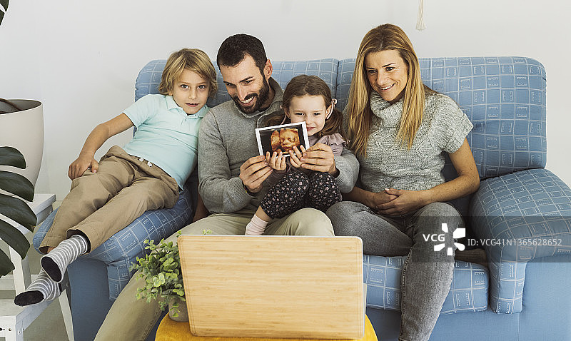 在家中通过笔记本电脑进行视频通话，分享超声波检查结果的微笑家庭图片素材