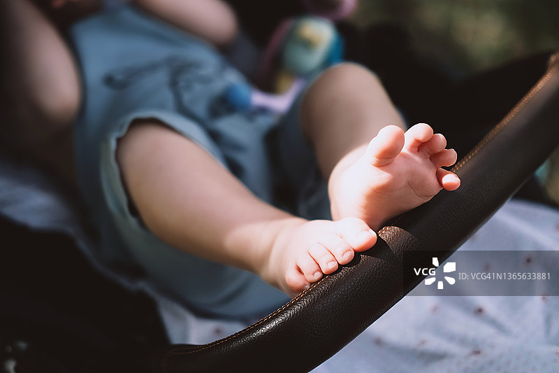 在婴儿车里用脚触摸扶手的宝宝图片素材