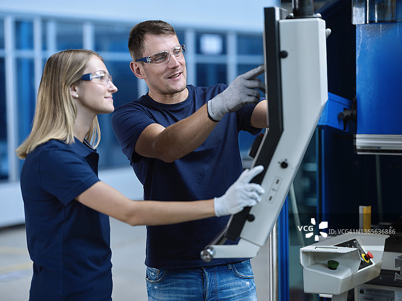 佩戴防护眼镜的技术人员讨论数控机床图片素材