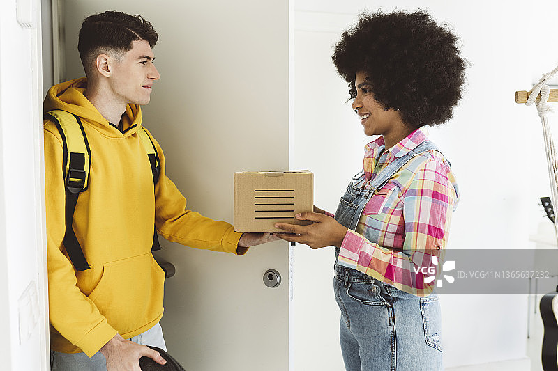 年轻男子将包裹送到微笑的女人门口图片素材