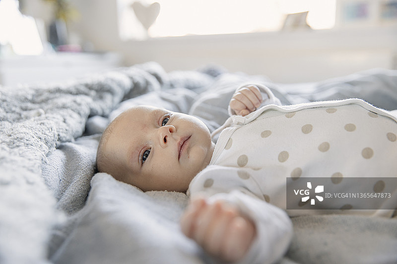 可爱的女宝宝躺在床上看着镜头图片素材