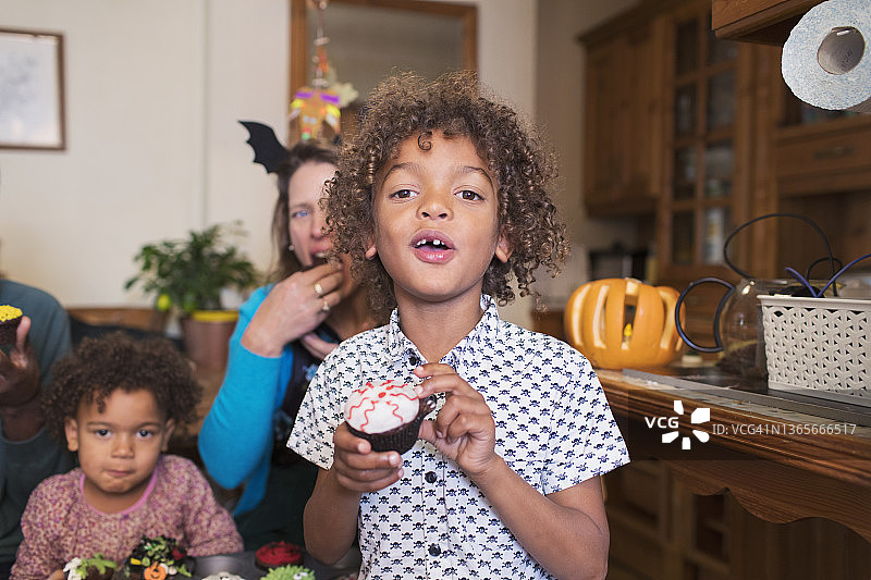 男孩吃万圣节纸杯蛋糕的肖像图片素材