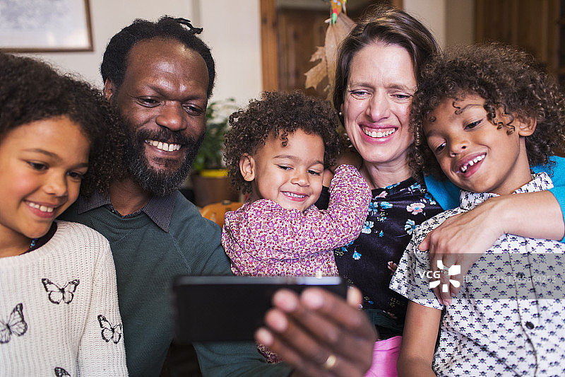 快乐的跨种族家庭用手机自拍图片素材