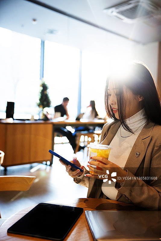 在咖啡馆使用手机的年轻女商人图片素材