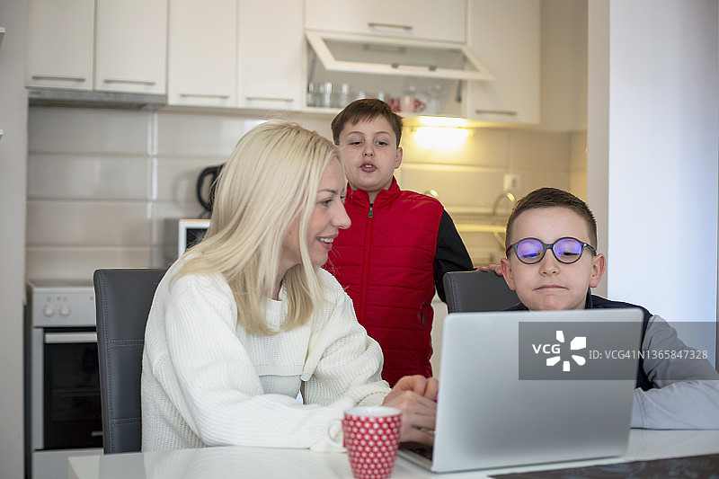 母亲和儿子们在笔记本电脑上看电视图片素材