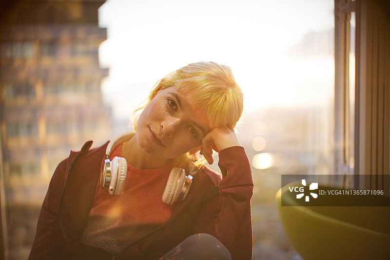 戴着耳机在办公室窗口的年轻女商人肖像图片素材