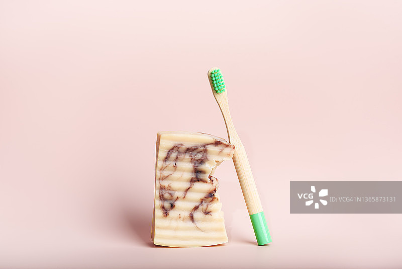 粉色背景上手工皂旁边的环保天然竹牙刷图片素材