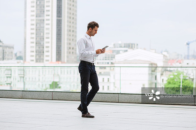 年轻商人外出中使用平板电脑图片素材