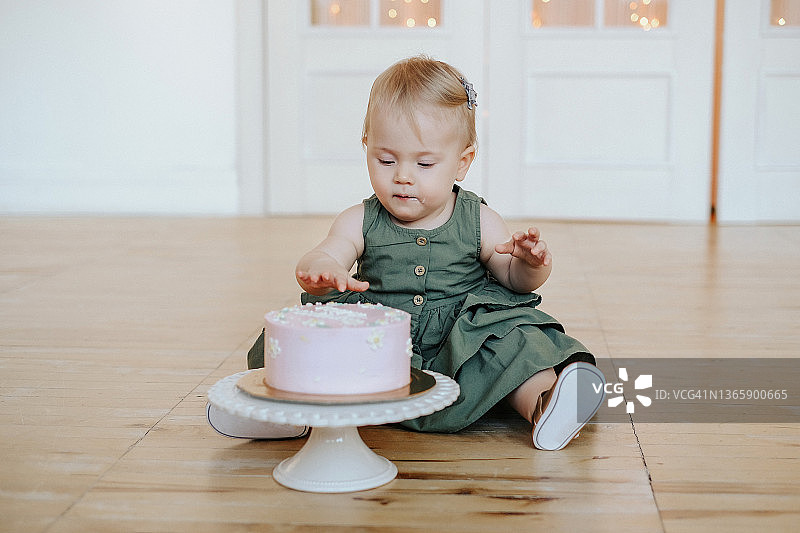 可爱的小女孩用手吃蛋糕特写：弄脏脸的一岁宝宝图片素材