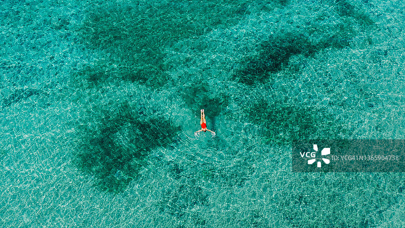 阿尔巴尼亚，绿松石色海水中穿红色泳衣的女子鸟瞰图片素材
