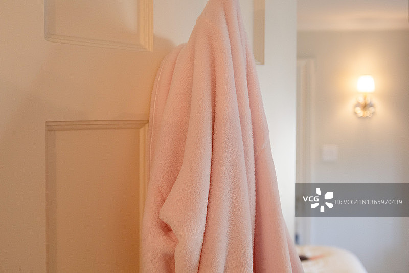 粉色浴袍挂在浴室门钩上，可看到卧室图片素材