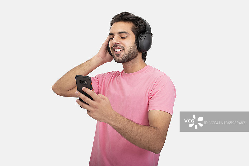 使用手机并戴着耳机听音乐的年轻男人图片素材