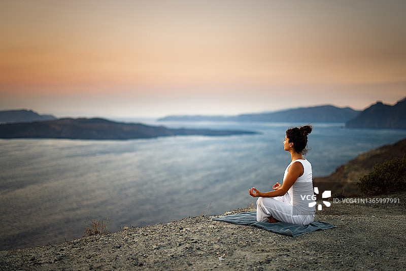 在海边山丘上冥想的放松女子图片素材