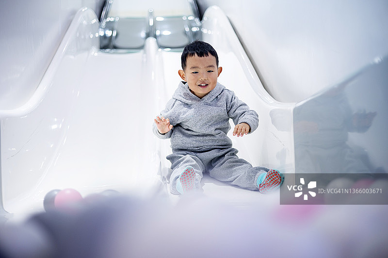 快乐的小男孩在操场上滑滑梯图片素材