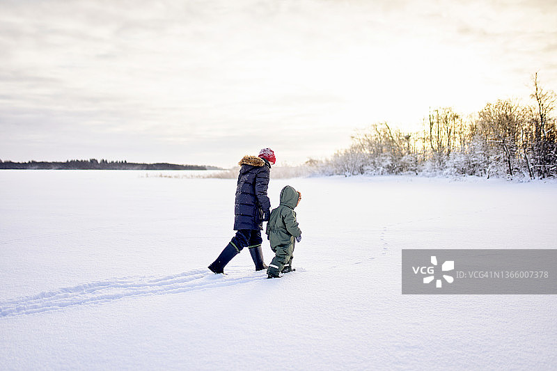 两个男孩，两个兄弟在大自然的雪地里散步。图片素材