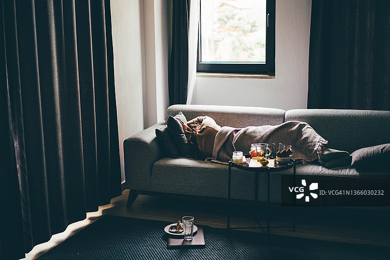 在家中沙发上躺着的焦虑年轻女子图片素材