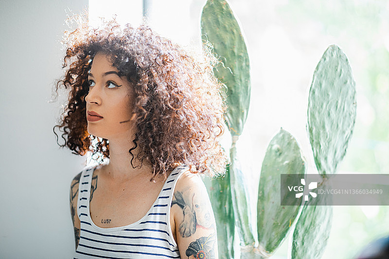 在窗边抬头看的卷发化妆年轻女子图片素材