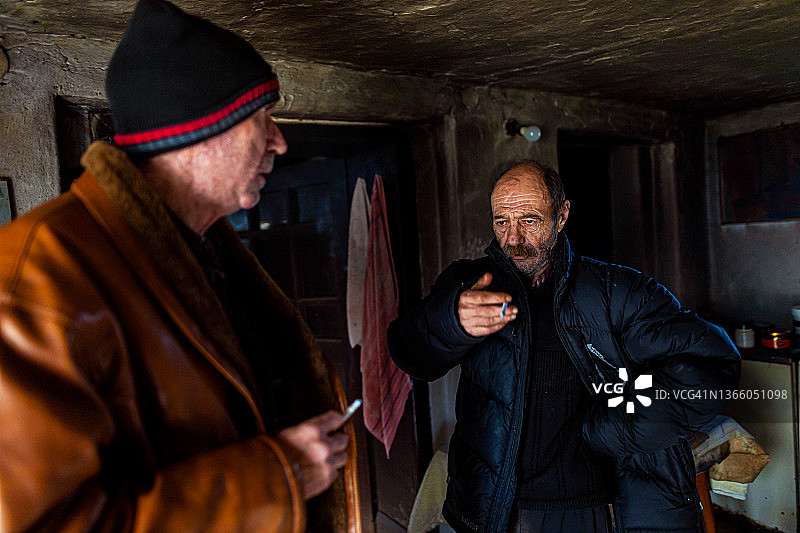 在流浪者收容所交谈和吸烟的年长的流浪男人图片素材