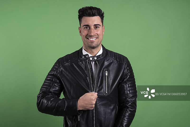 在绿色背景下微笑并看向镜头的迷人男人图片素材