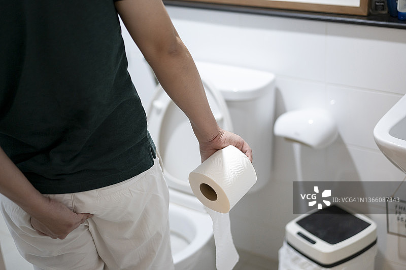 在浴室里拿着卫生纸卷的男人图片素材