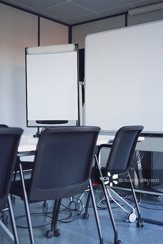 会议室里一排空椅子，远程办公普及，配有活动挂图和白板，以及缠绕的电缆图片素材