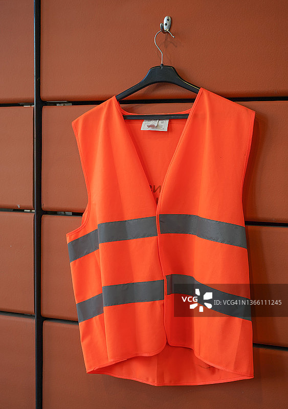 挂在橙色墙上的橙色荧光条纹背心图片素材