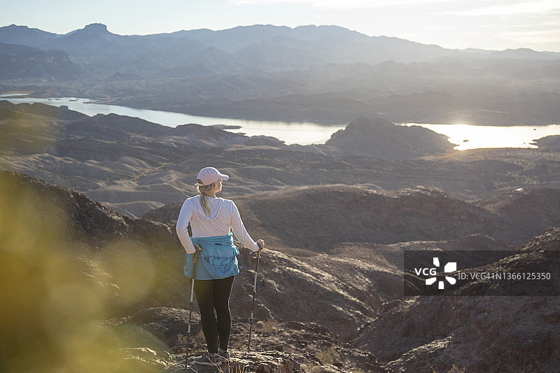 女人徒步穿越阳光明媚的沙漠景观图片素材
