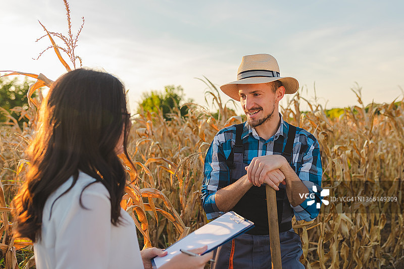 年轻的男农民与女农业检查员交谈有关农作物图片素材