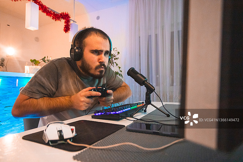 专注的年轻男玩家戴着耳机直播游戏图片素材