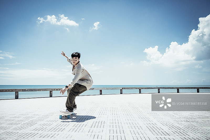 在美丽的夏日户外玩滑板的亚洲男人图片素材