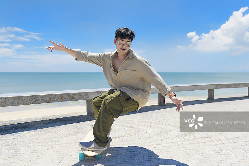 在美丽的夏日户外玩滑板的亚洲男人图片素材