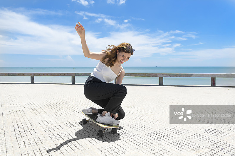 在美丽的夏日里，玩冲浪滑板的亚洲女性图片素材