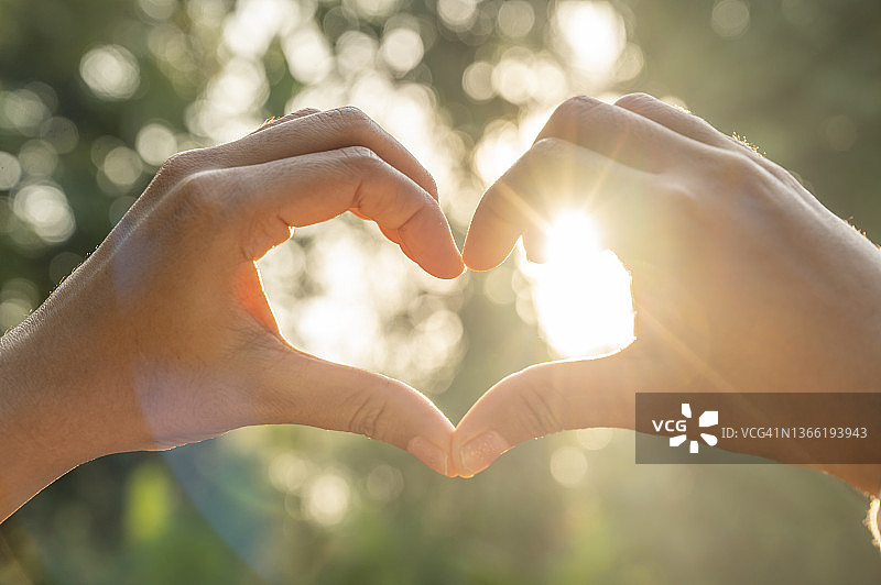 阳光穿过情侣手中的爱心图片素材