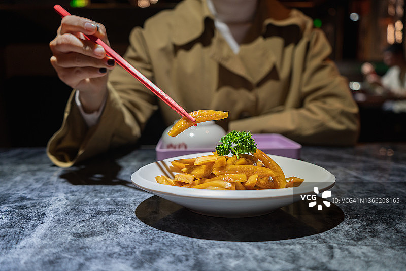 一只手用筷子从盘子里夹起一块酸萝卜图片素材