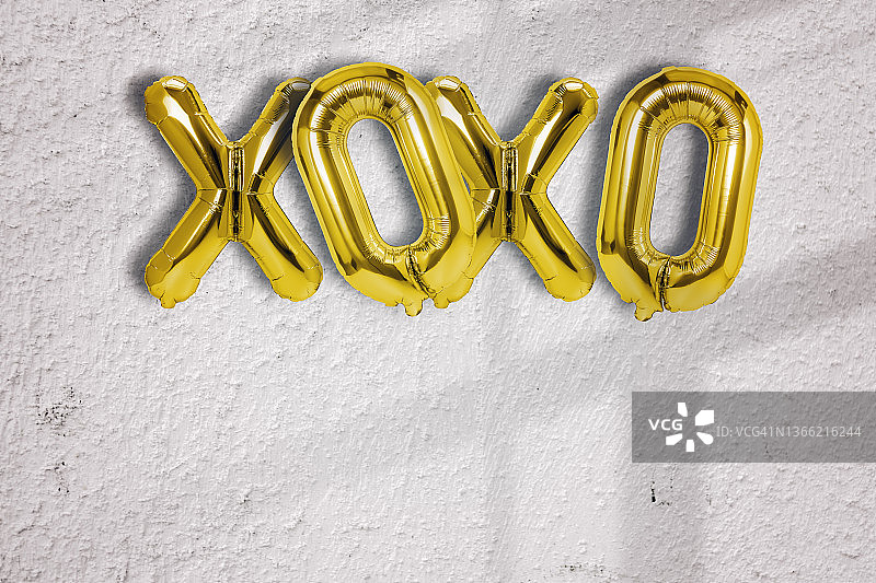 金色箔气球XOXO单字，白色砖墙背景图片素材