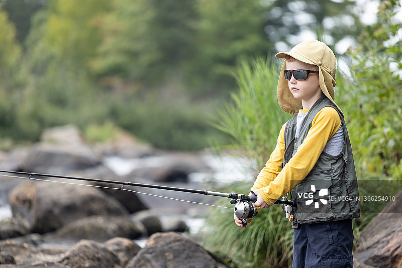 在魁北克河里钓鱼的可爱红发男孩图片素材