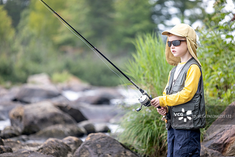 在魁北克河里钓鱼的可爱红发男孩图片素材