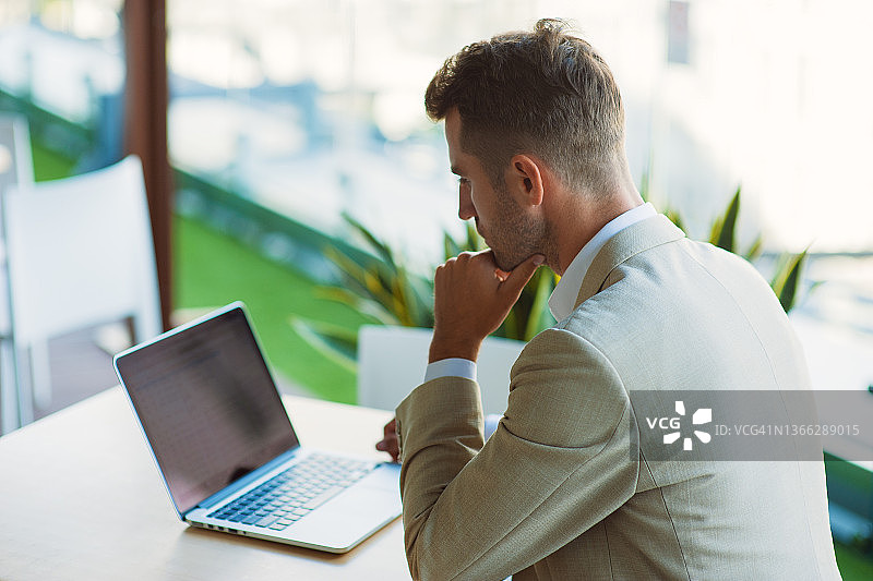 在咖啡馆里，商人使用手机App和笔记本电脑进行股票市场交易图片素材