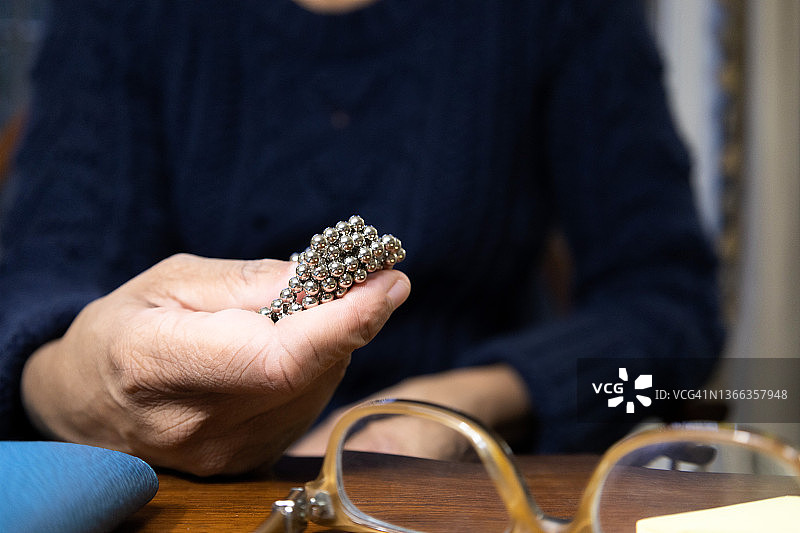 在家办公桌前工作的黑人女性拿着磁性玩具图片素材