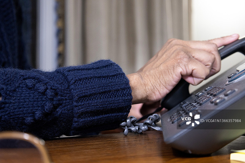 黑人女子在家居办公室的桌旁使用座机电话图片素材