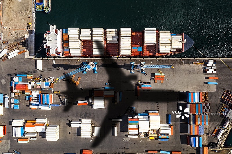 商业港口货船和集装箱上的飞机阴影：全球运输概念图片素材