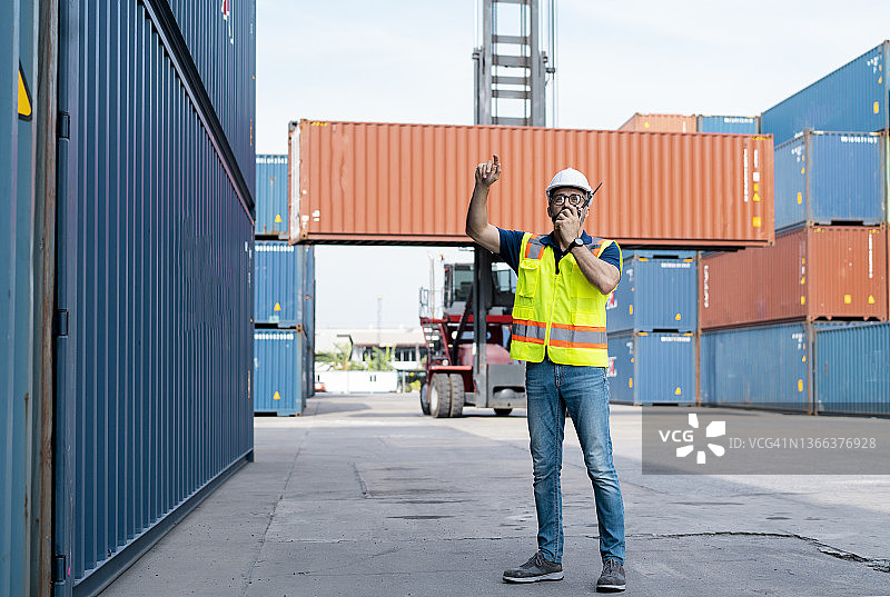 穿着工作服在商业码头上用对讲机交谈的男子图片素材