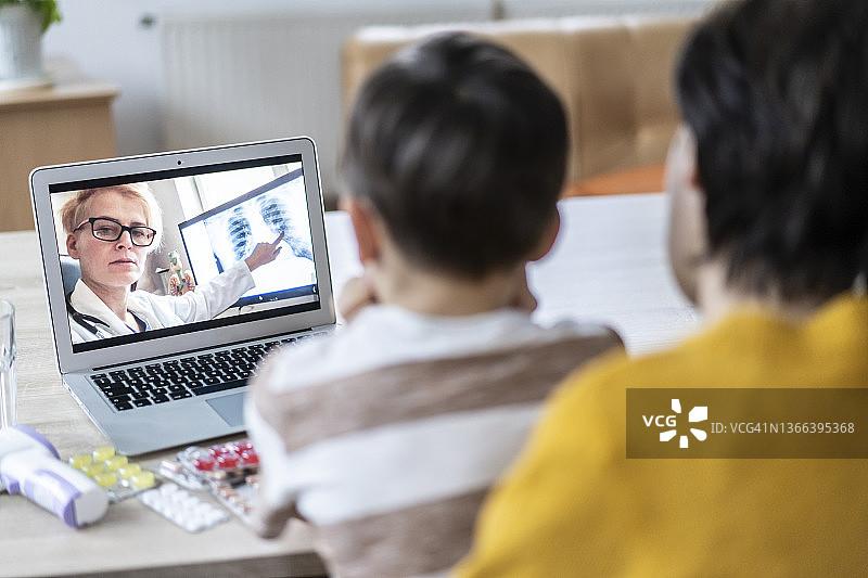 母亲和儿子在家与医生视频通话图片素材
