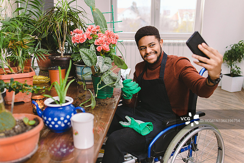 非裔美国残疾青年在家中享受照顾植物的时光图片素材
