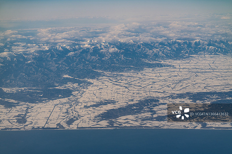 从飞机上俯瞰日本北海道日高山脉、大树町和更别村的雪景图片素材