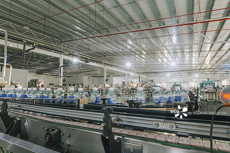 矿泉水厂生产线：瓶子在贴标包装线上排队移动图片素材