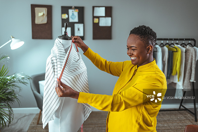 裁缝在工作室调整人体模型上的服装设计图片素材