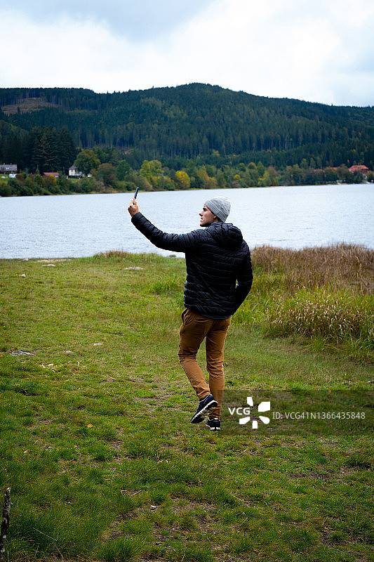 年轻男人在冬天走向湖边图片素材