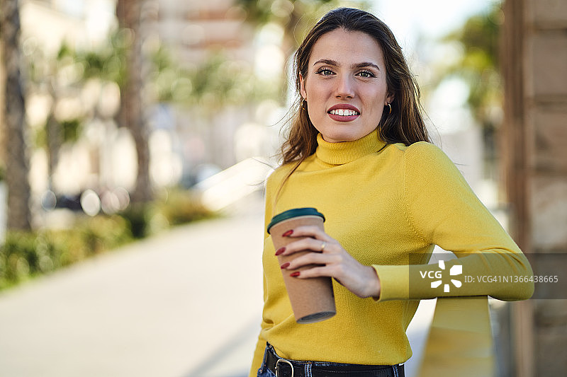 快乐的女人靠在栅栏上浏览智能手机图片素材