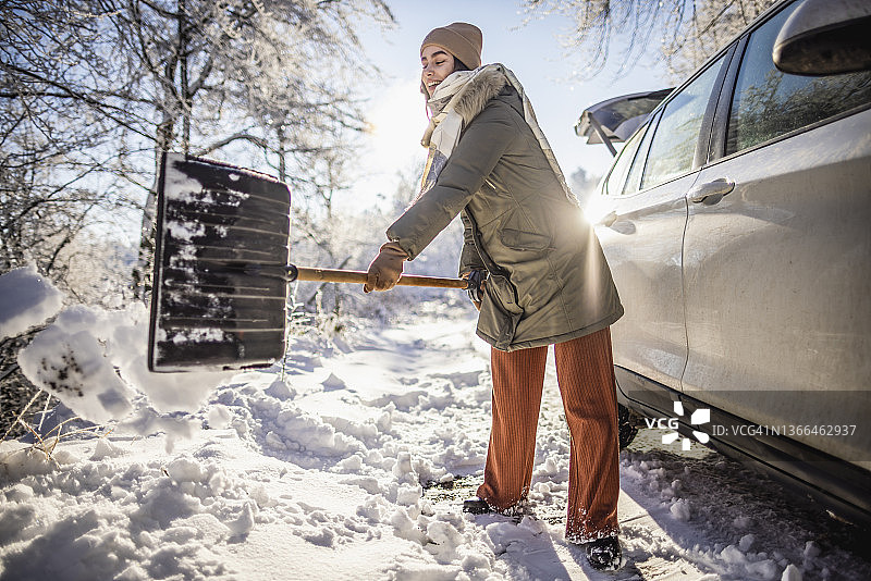 女人在户外清理车旁的积雪图片素材
